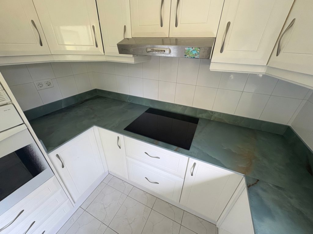 Green marble-effect porcelain kitchen countertop installed in Benalmádena with white cabinets