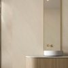Detalle de revestimiento Ascale Arena Sand en baño con lavabo y grifería dorad