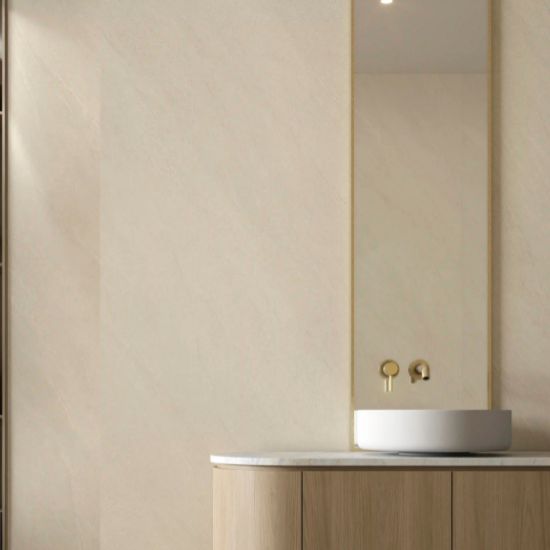 Detalle de revestimiento Ascale Arena Sand en baño con lavabo y grifería dorad